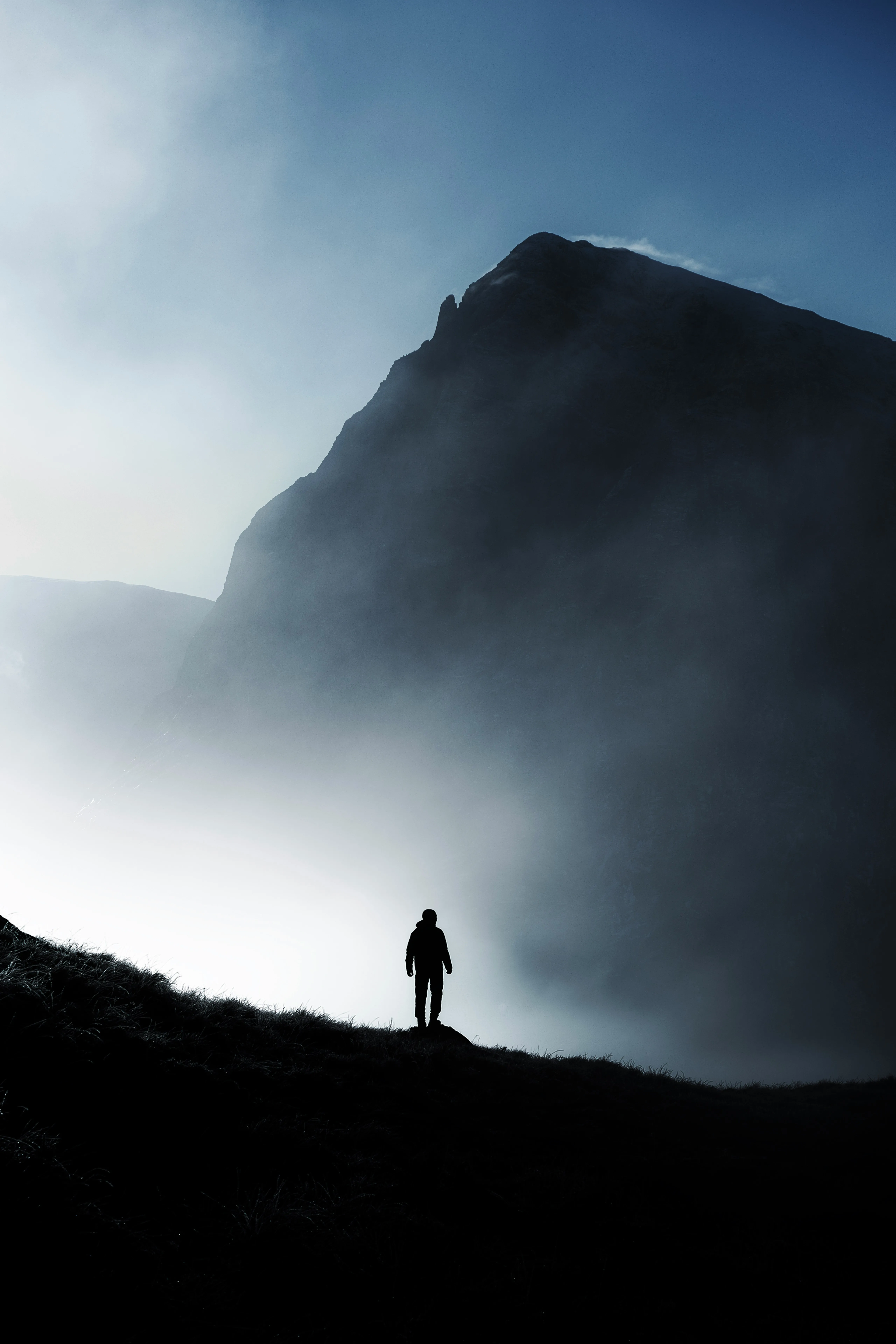 Man standing before fog-shrouded mountain