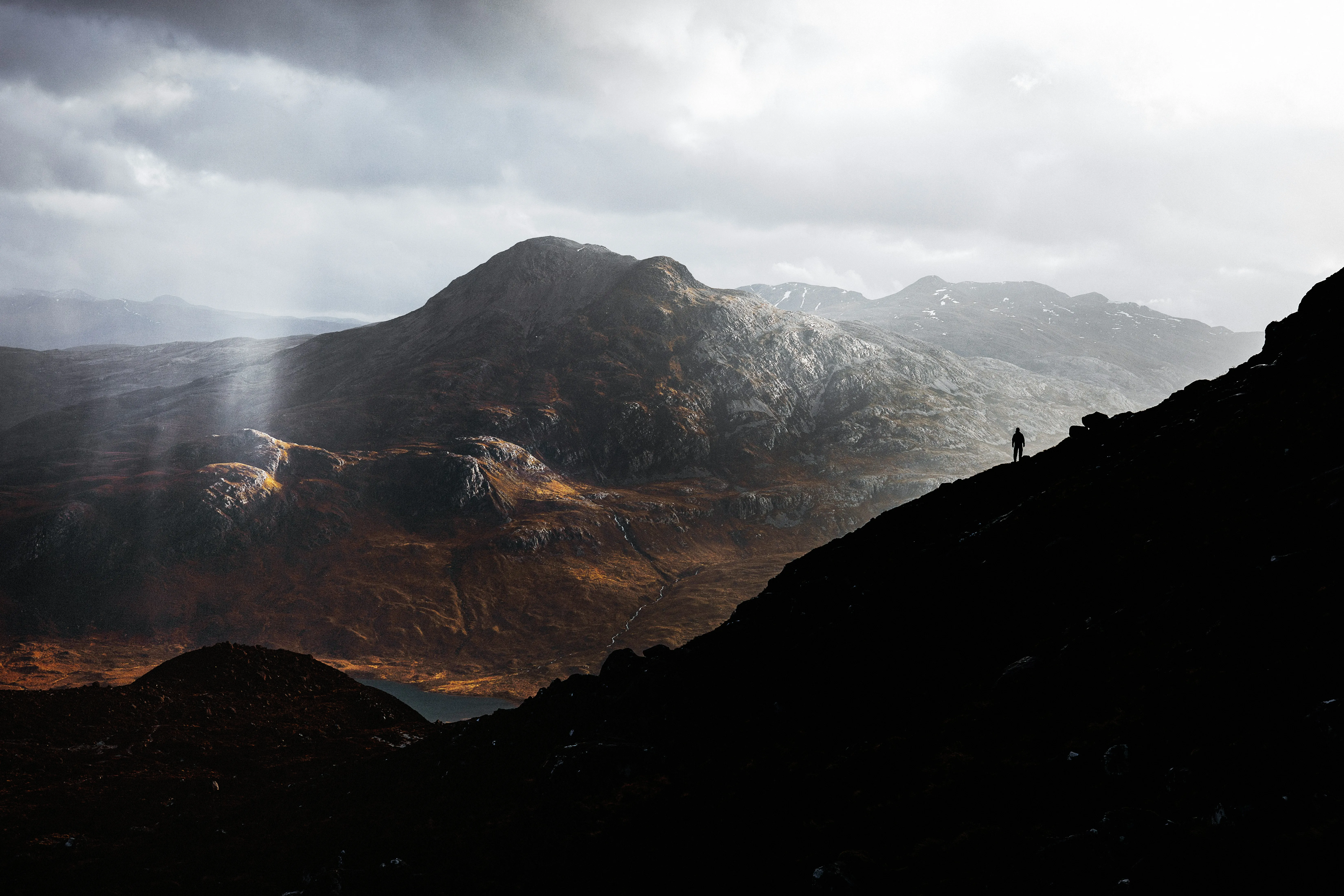 Man on ridge with light breaking through storm clouds