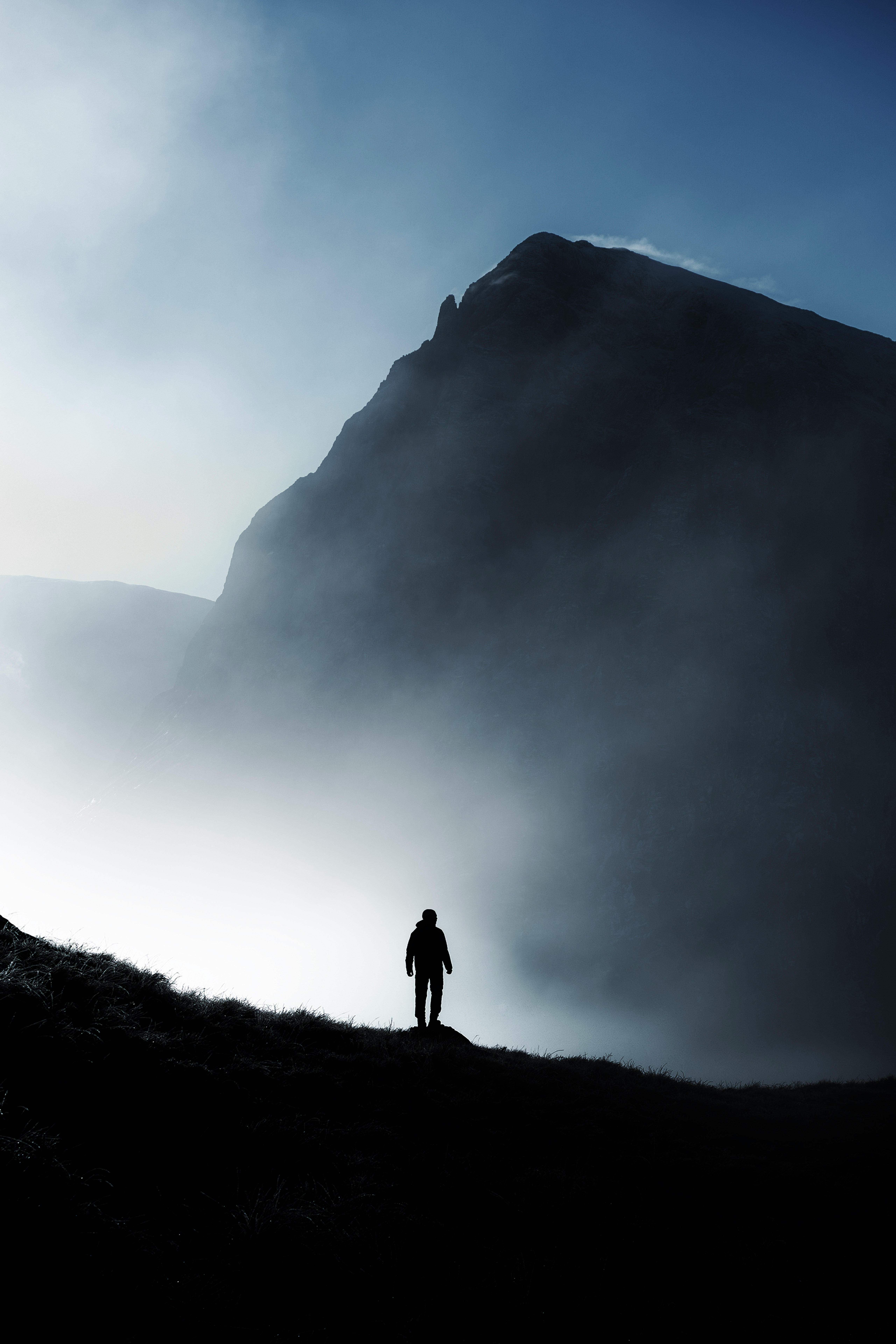 Man standing before fog-shrouded mountain